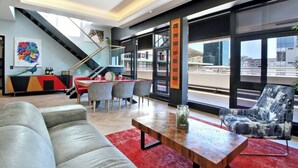 A modern living room with a sofa, a coffee table, and a chair. There is a staircase leading to an upper level. - Onyx Penthouse by ITC Hospitality (Cape Town)