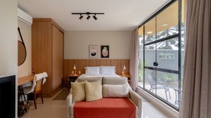 Une chambre d’hôtel comprenant un lit, des tables de chevet, une chaise, une cheminée et une grande fenêtre donnant sur l’extérieur.