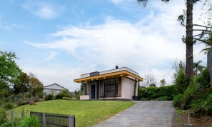 A modern house with a paved driveway leading to a front door, surrounded by lush greenery and trees. - House w/ Fireplace and Bathtub in Urubici Cla0000 (Urubici)