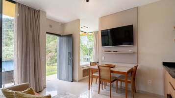 A modern living room with a flat-screen TV, wooden dining table, and chairs.