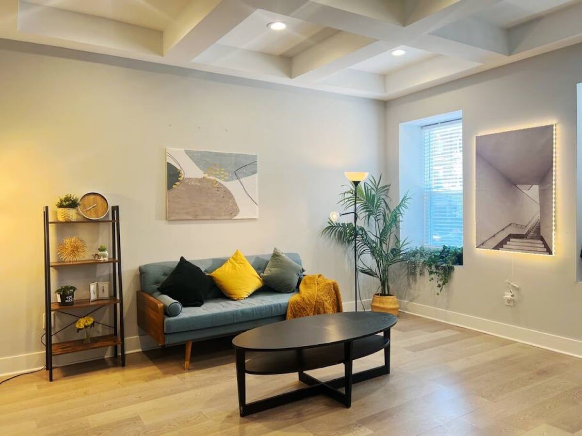 A living room with a blue sofa, a black coffee table, and a plant.