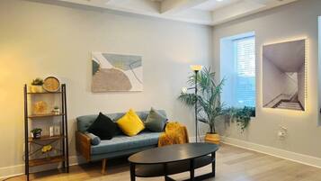 A living room with a blue sofa, a black coffee table, and a plant.