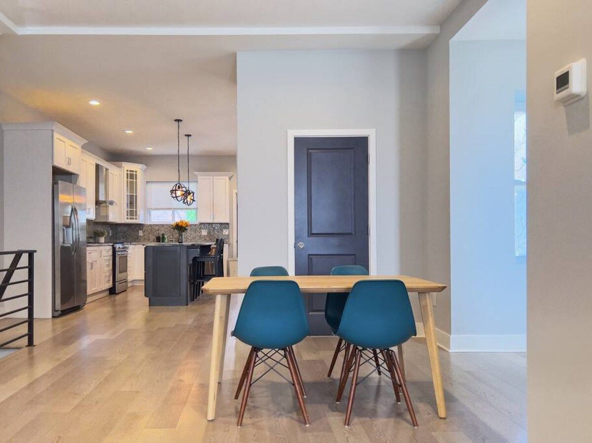 Cocina moderna con comedor, que incluye una mesa de madera y sillas azules.