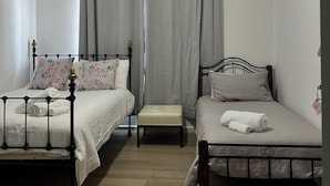 A bedroom with two beds, a ceiling fan, and a window with curtains.