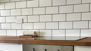A kitchen with a stainless steel oven, white cabinets, and a wooden countertop.