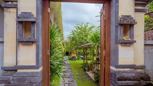 Un chemin menant à un bâtiment traditionnel, avec des marches en pierre et un petit jardin agrémenté de palmiers.