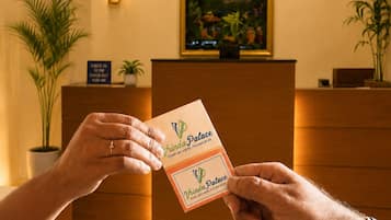 A reception desk with a framed picture, a ceiling fan, and a sign indicating check-in and check-out times.