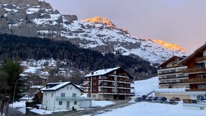 A mountain resort with multi-story buildings, a parking area, and a snow-covered landscape. - Spacious 3.5-Room | Best Location • Free Parking (Leukerbad)