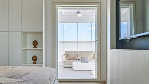 Une chambre moderne avec un lit, un bureau avec un ordinateur portable et un canapé dans le salon attenant.