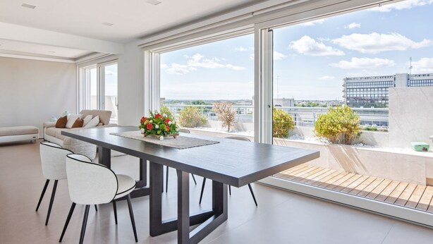 Un salon moderne avec un coin repas, de grandes fenêtres et une vue sur le paysage urbain.