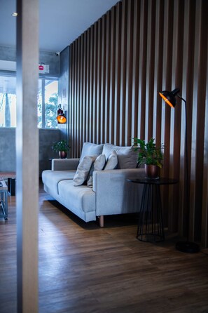 A modern living room with a grey sofa, wooden slatted wall, and a small round table with a lamp. - Blue Tree Towers Sorriso (Sorriso)