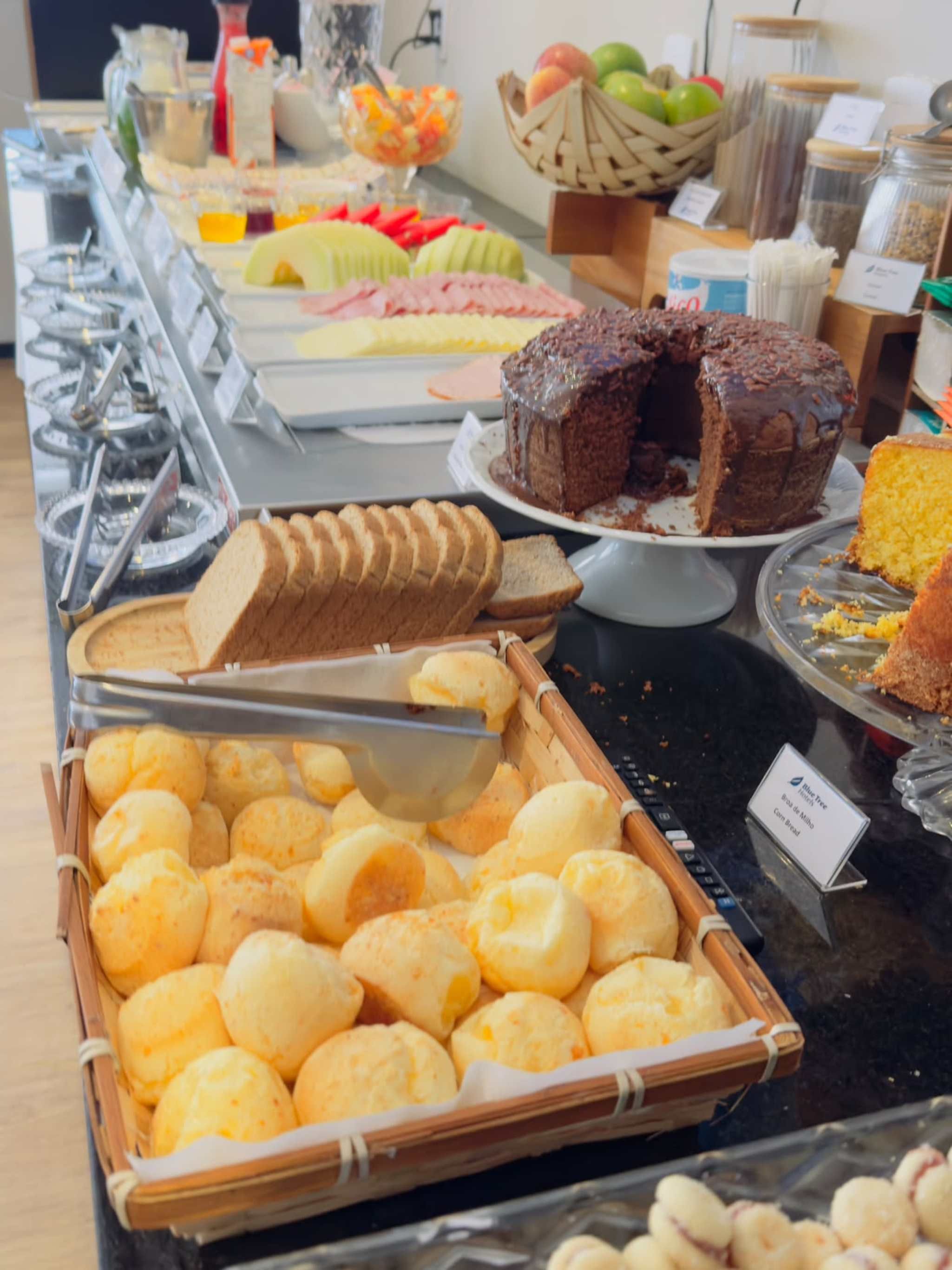 Een buffet met diverse soorten eten, zoals brood, gebak en een keuze uit fruit.