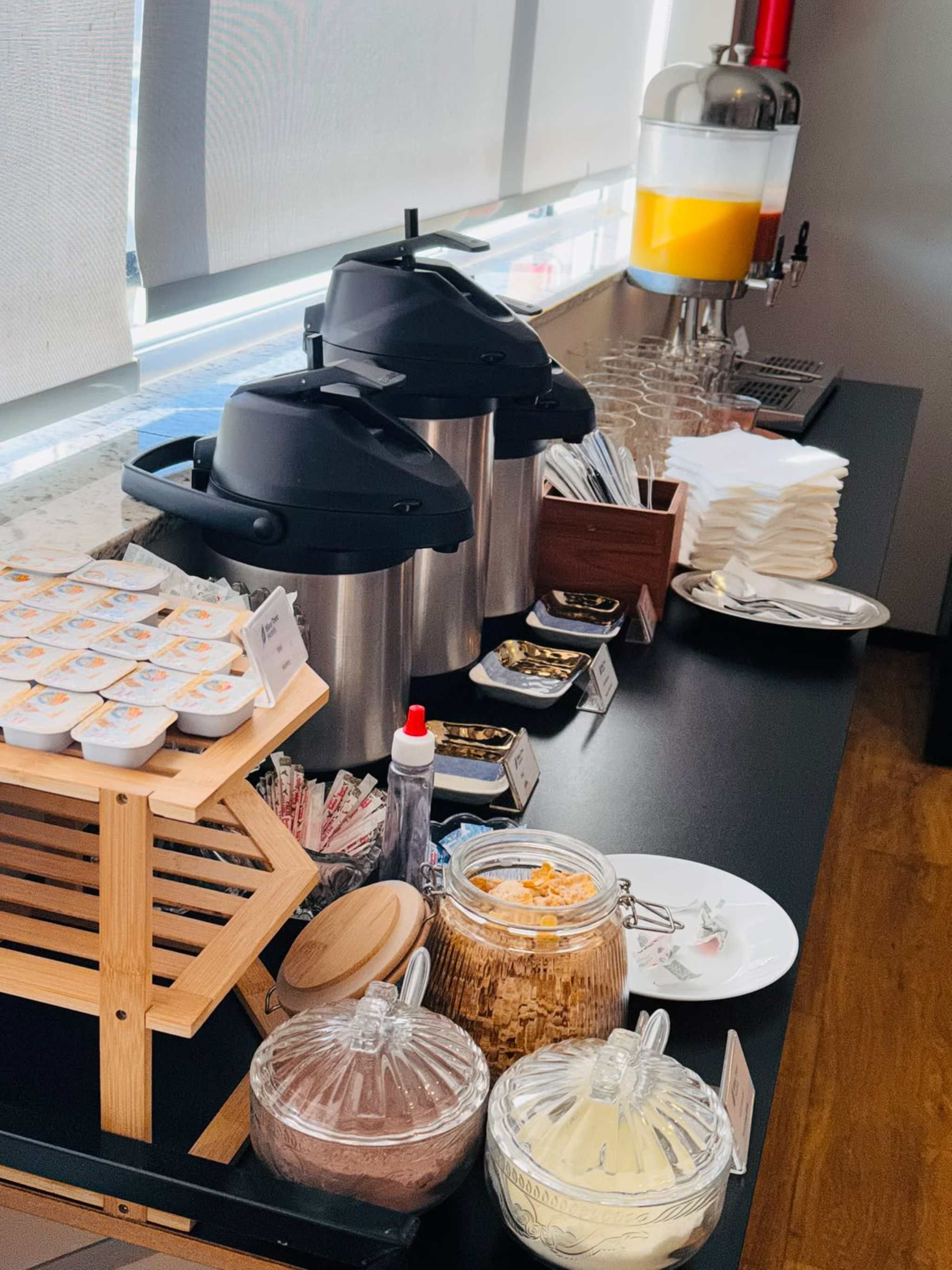 A buffet setup with various food items, a coffee machine, and condiments.