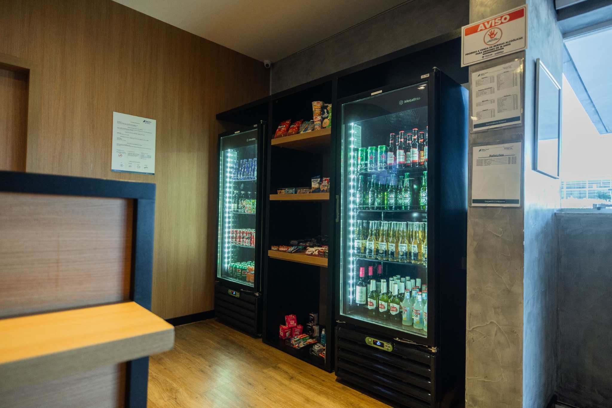 Een bar met twee verlichte drankdispensers, een houten toonbank en een menukaart aan de muur.