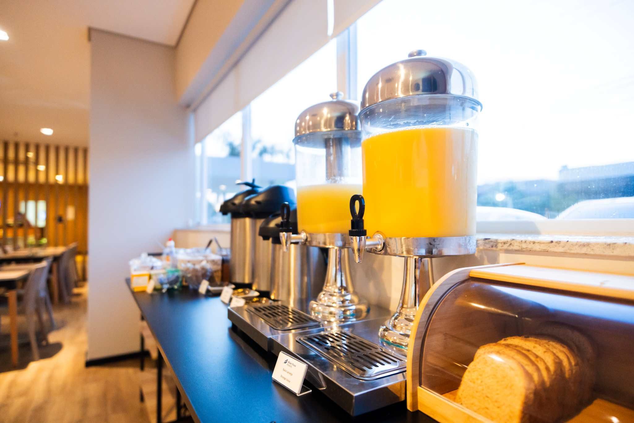 A breakfast bar with juice dispensers and a bread display.