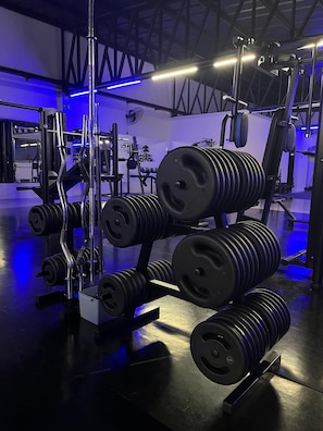 Ein Fitnessraum mit Krafttrainingsgeräten, darunter Kurzhanteln und Langhanteln.