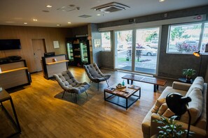 A modern interior with a reception desk, seating area, and a large window offering a view of the parking lot. - Blue Tree Towers Sorriso (Sorriso)