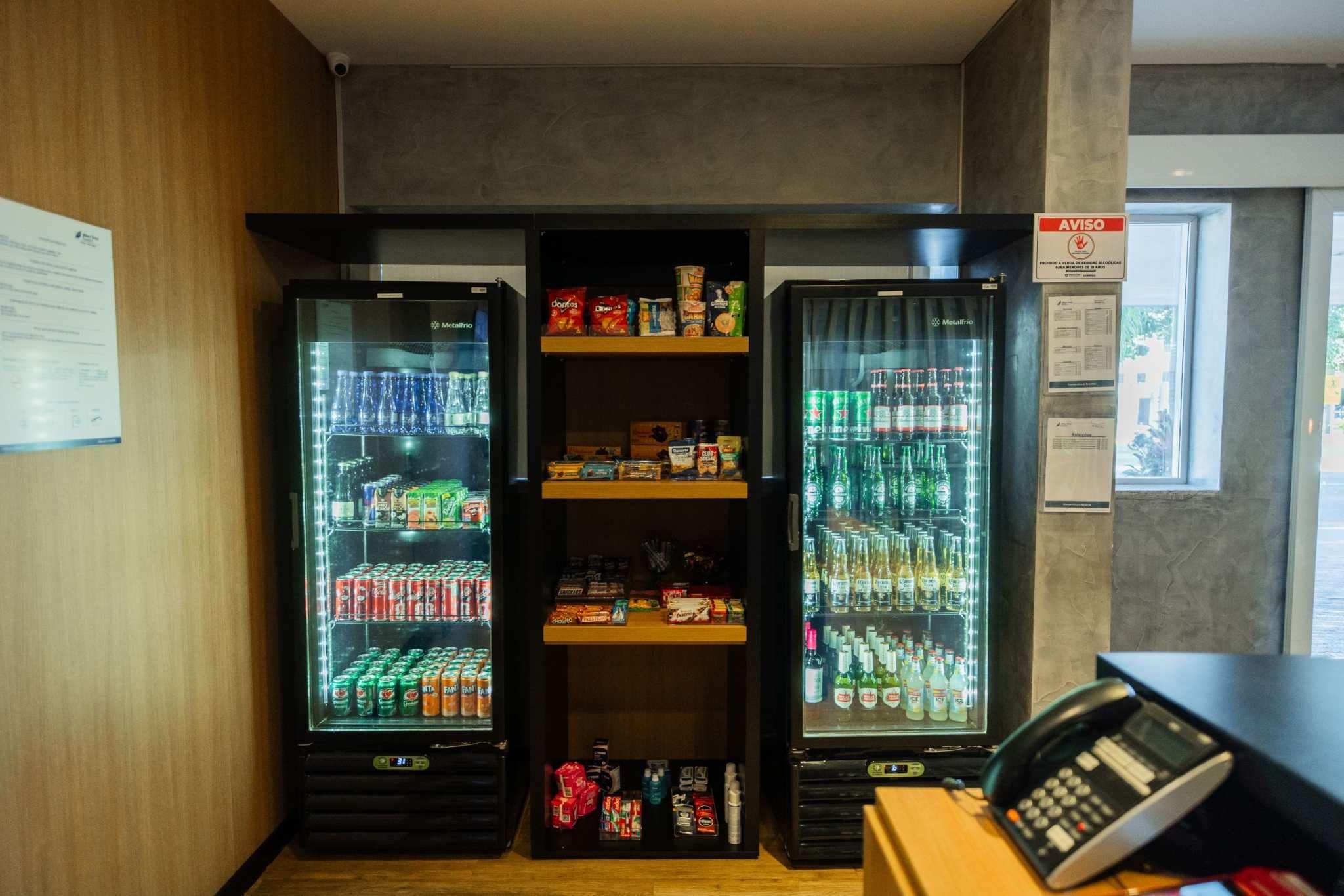 A vending machine area with three refrigerated units, a phone, and a window with a view.