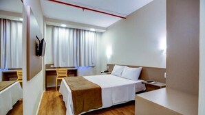 A hotel room with a bed, bedside table, desk, chair, and a large mirror. - Blue Tree Towers Sorriso (Sorriso)