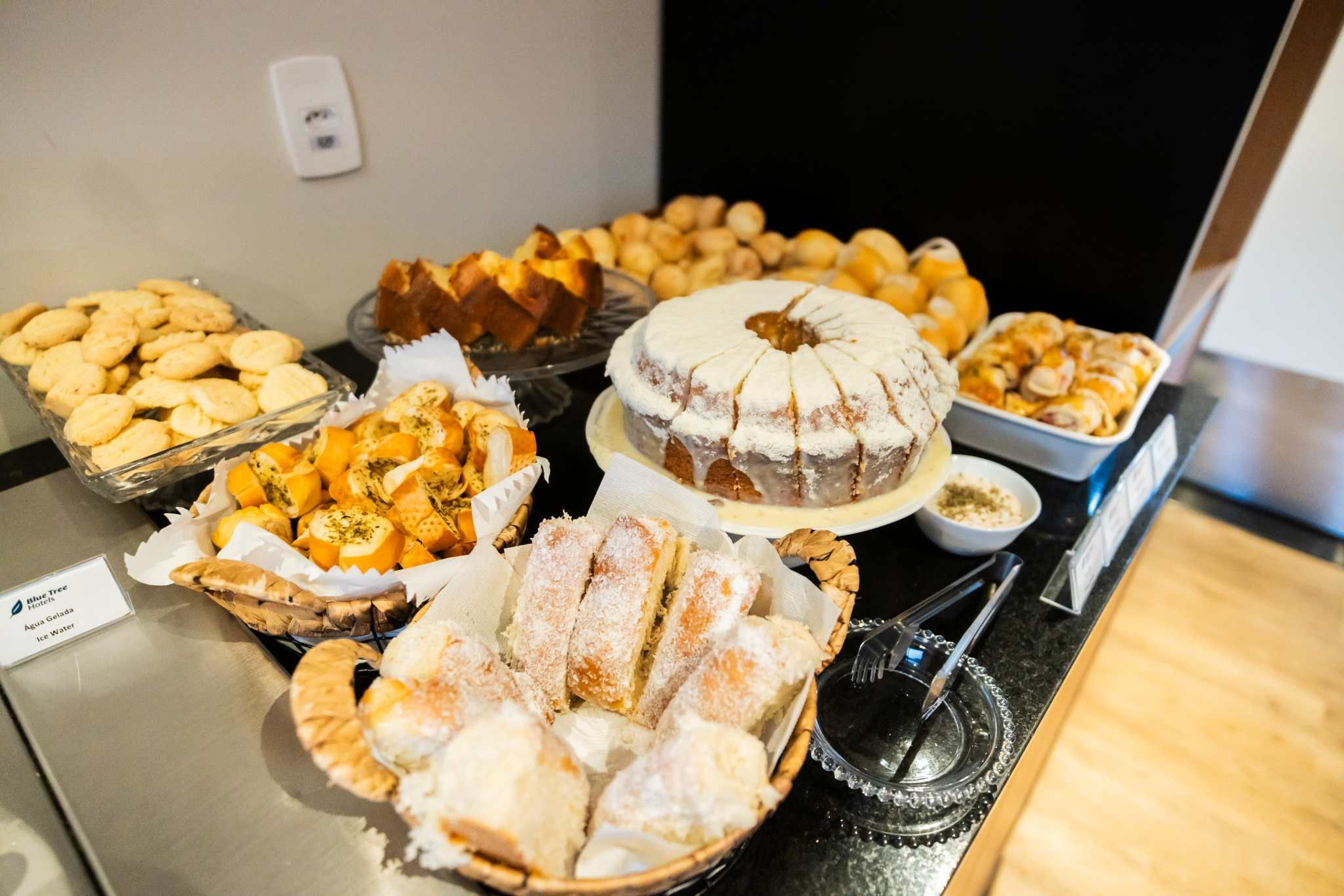 A buffet table with various baked goods including pastries, bread, and desserts.