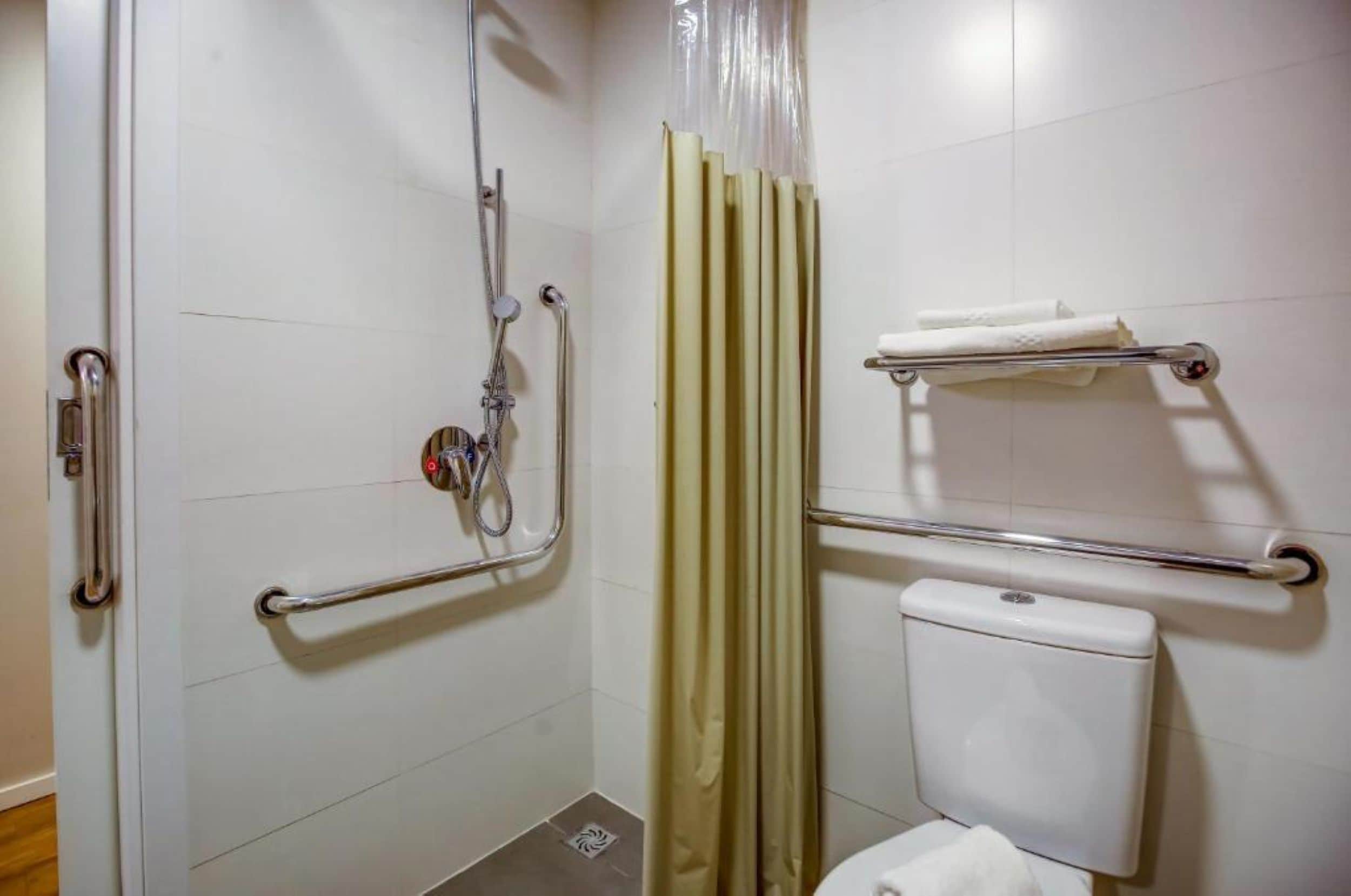 Une salle de bain équipée d’une douche, de toilettes et de barres d’appui.
