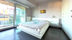 Une chambre moderne avec un grand lit, une fenêtre et un radiateur.