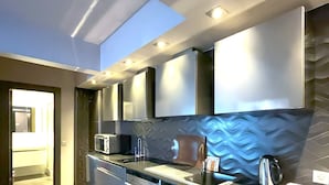 Une cuisine moderne dotée d’appareils électroménagers en acier inoxydable, d’un grand îlot central et d’un revêtement mural décoratif.