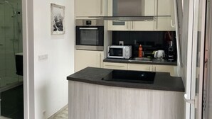 A modern kitchen with a built-in microwave, oven, and stainless steel range hood. - New Studio | Dream Views • Balcony • Free Parking (Leukerbad)