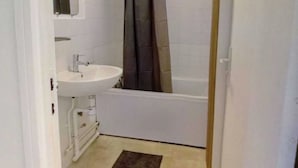 Une salle de bain avec un lavabo blanc, un miroir, un rideau de douche et une baignoire.