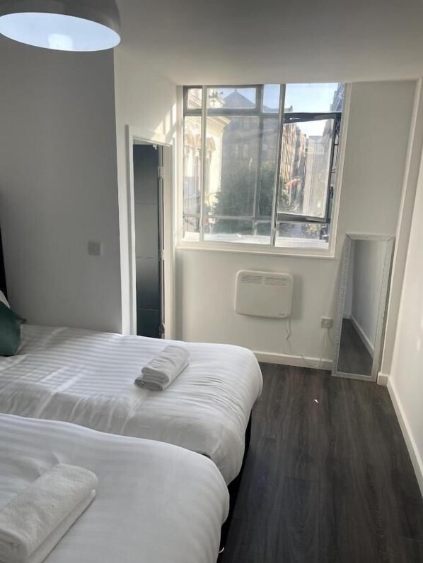 Une chambre d’hôtel avec deux lits, une fenêtre et un radiateur.
