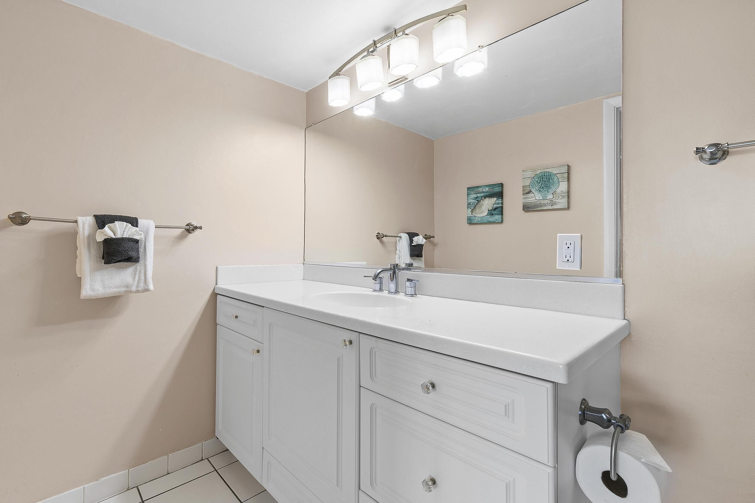 Une salle de bain avec un meuble-lavabo blanc, un grand miroir et un porte-serviettes.