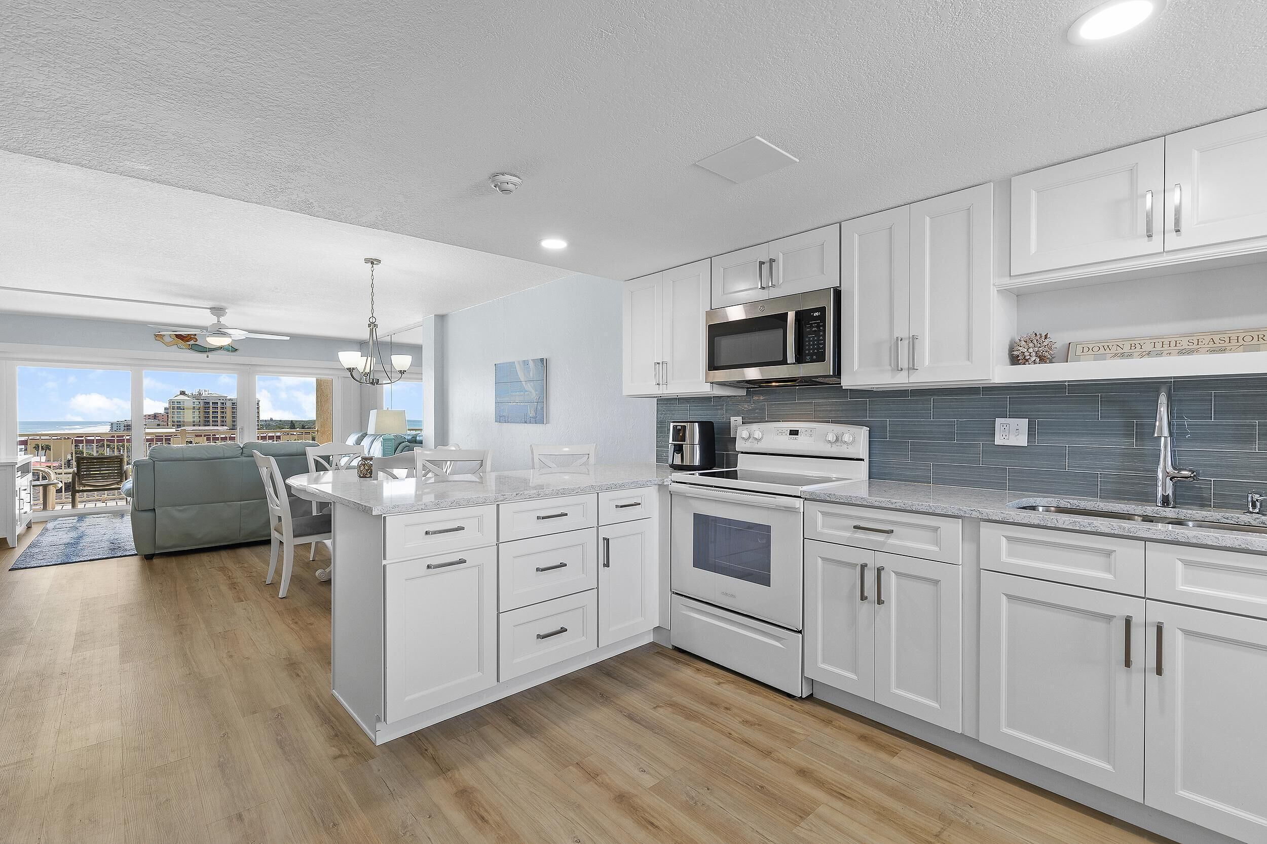A modern kitchen with white cabinetry, a stainless steel microwave, and an oven.