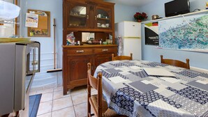 Une pièce de taille modeste comprenant un lit, une armoire en bois, un réfrigérateur et un téléviseur fixé au mur.
