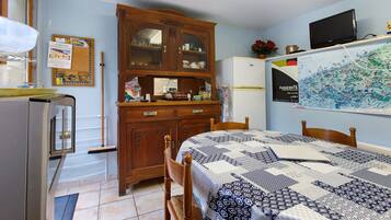 Une pièce de taille modeste comprenant un lit, une armoire en bois, un réfrigérateur et un téléviseur fixé au mur.