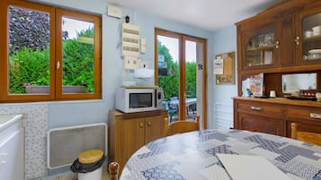 Een keuken met een magnetron, een spoelbak en een raam met uitzicht op groen.