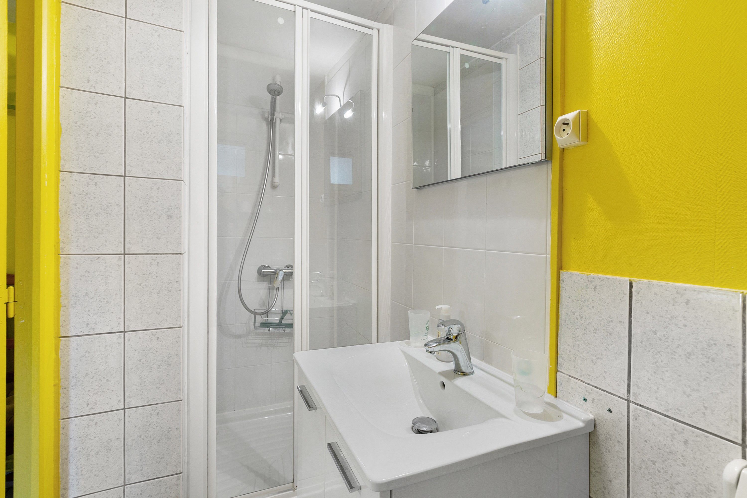 Een badkamer met een douche, een wastafel en een spiegel.