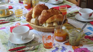 A breakfast setting with croissants, coffee cups, and a wicker basket. - Bed and Breakfast 'Chambre Lecarpentier - Tulipe' with Shared Terrace, Shared Garden and Wi-Fi (Fontenay)