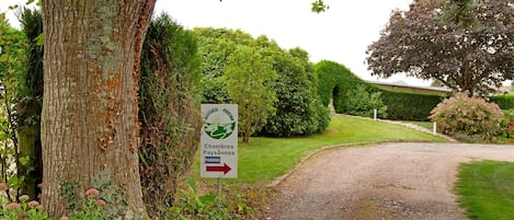 A gravel path leading to a sign indicating a parking area for 'Chambres Paysannes'.