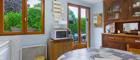 Una cocina con microondas, un lavamanos y una ventana con vistas a la vegetación.
