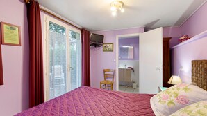 A bedroom with a bed, a chair, a television, and a bathroom visible through an open door. - Guest Room 'Chambre Lecarpentier - Pensée' with Shared Terrace, Shared Garden and Wi-Fi (Fontenay)