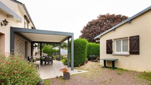 A covered patio area with outdoor furniture, a gravel path, and a garden with various plants and flowers. - Guest Room 'Chambre Lecarpentier - Pensée' with Shared Terrace, Shared Garden and Wi-Fi (Fontenay)