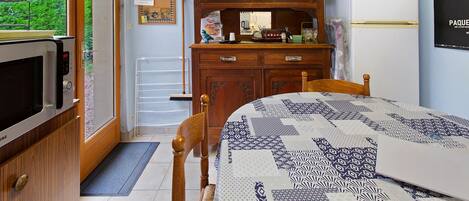 A compact kitchen with a microwave, a refrigerator, and a wooden cabinet with glass doors.