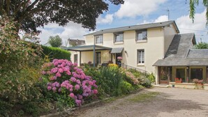 A two-story house with a front porch, a driveway, and a garden with pink flowers. - Guest Room 'Chambre Lecarpentier - Pensée' with Shared Terrace, Shared Garden and Wi-Fi (Fontenay)
