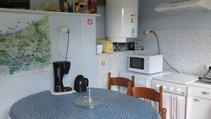 A kitchen with a round table, chairs, a stove, a microwave, a water heater, and a TV. - Guest Room 'Chambre Lecarpentier - Pensée' with Shared Terrace, Shared Garden and Wi-Fi (Fontenay)