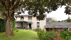 A two-story house with a front lawn, a large tree, and a variety of plants and flowers. - Guest Room 'Chambre Lecarpentier - Pensée' with Shared Terrace, Shared Garden and Wi-Fi (Fontenay)