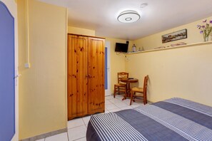 A room with a bed, a wooden wardrobe, a television on the wall, and a small table with chairs. - Family Room Lecarpentier - Coquillage (Fontenay)