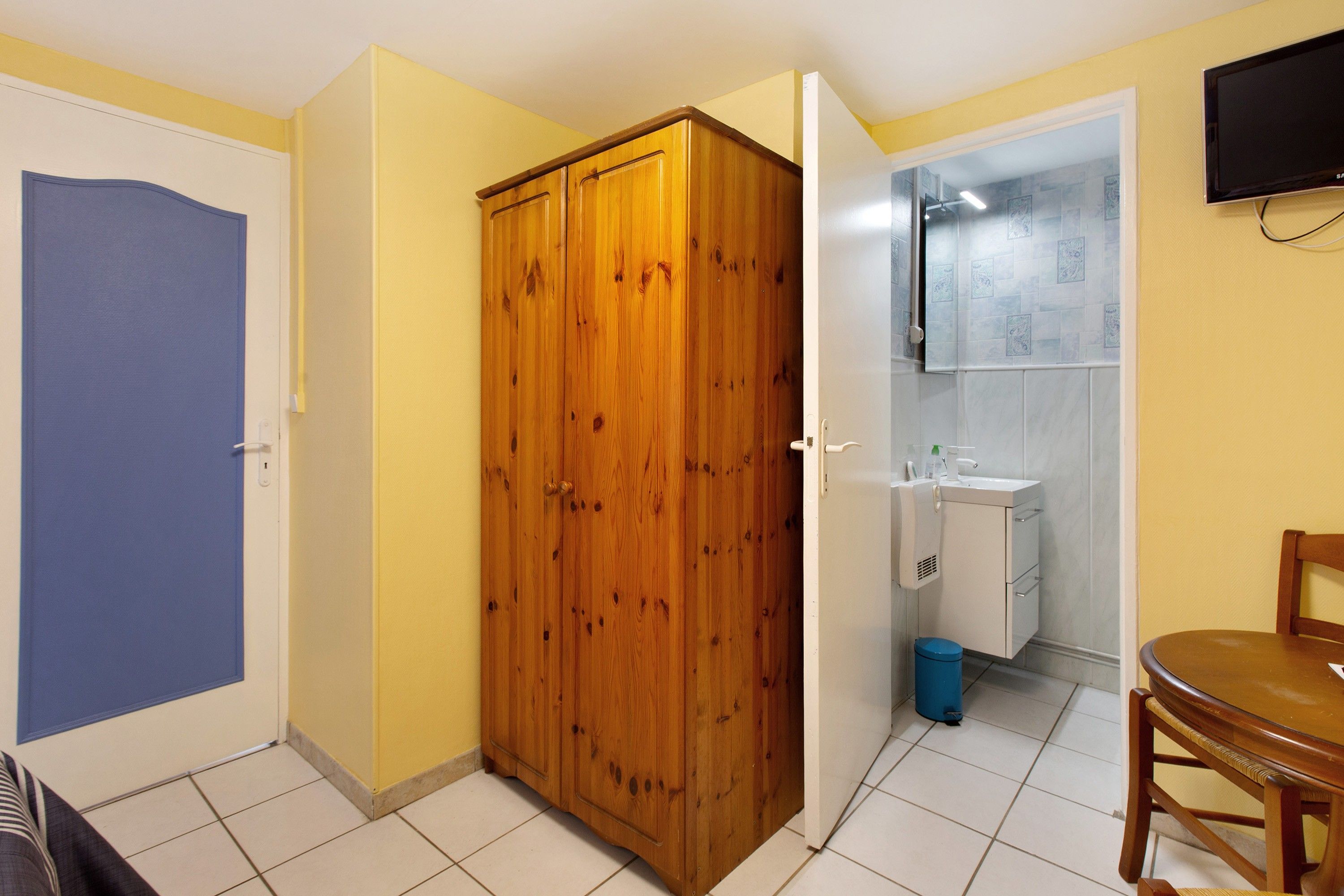 Une chambre avec un placard, une salle de bain avec un lavabo et une chaise.
