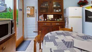 A compact kitchen with a microwave, a refrigerator, and a wooden cabinet with glass doors.