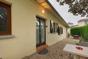 A building with a beige exterior, a door with a glass panel, and a small outdoor seating area with a table and chairs.