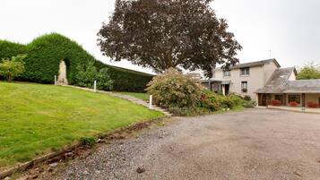 A residential property with a gravel driveway, a well-maintained lawn, and a large tree.